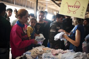 A Syrian woman looks for clothes for her baby at the Mixer House in Belgrade, Serbia. CRS, working with Caritas, organized a distribution center providing hygiene kits containing soap, shampoo, sanitary napkins, toothbrushes, toothpaste, diapers, clothing for infants and other basic supplies to the thousands of refugees traveling to Germany. Catholic Relief Services (CRS) and Caritas are scaling up their humanitarian relief efforts to address these growing needs in Serbia, Macedonia and Greece. This is part of the Balkan Refugees - Migrants Response project. Photos by Kira Horvath for Catholic Relief Services